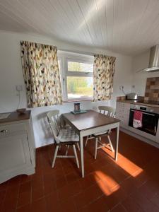 a kitchen with a table and two chairs and a window at Newfoundland Cottage in Whitechurch
