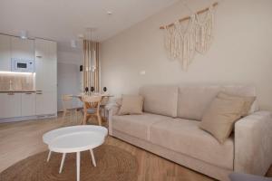 a living room with a couch and a table at Apartament Premium PINEA 107 in Pobierowo