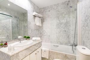 baño blanco con bañera, lavamanos y bañera tubermott en MARBELLA BANUS SUITES - Banus Playa Rocio Direct Sea Access en Marbella