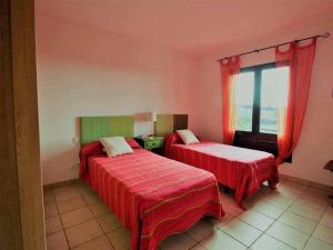 una camera con due letti con lenzuola rosse e una finestra di Apartamento La Cancela a Las Breñas