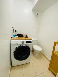 een wasmachine in een badkamer met een toilet bij Charmant appartement 3 pièces proche RER & Disney in Montévrain