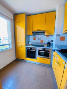 kuchnia z żółtymi szafkami i kuchenką w obiekcie Charmant appartement 3 pièces proche RER & Disney w mieście Montévrain