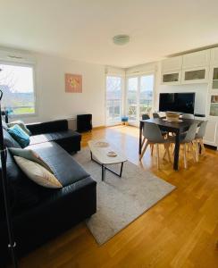 a living room with a black couch and a table at Charmant appartement 3 pièces proche RER & Disney in Montévrain