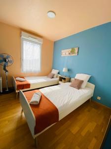 a bedroom with two beds and a blue wall at Charmant appartement 3 pièces proche RER & Disney in Montévrain