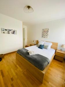 een slaapkamer met een groot bed en een houten vloer bij Charmant appartement 3 pièces proche RER & Disney in Montévrain