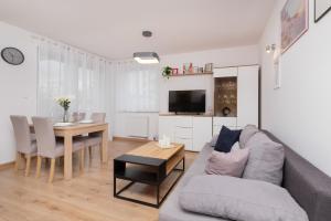 a living room with a couch and a table at Bright Apartment with Private Garden and Accepting Pets by Renters in Gdańsk