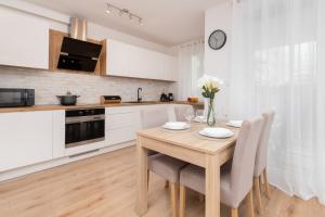 a kitchen with a wooden table and chairs in a kitchen at Bright Apartment with Private Garden and Accepting Pets by Renters in Gdańsk