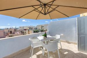 d'une table et de chaises sur un balcon avec un parasol dans l'établissement Beautiful 2BR Penthouse with Private Terrace & BBQ by 360 Estates, à San Pawl il-Baħar