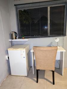 a kitchen with a table and a refrigerator and a chair at Sem's Guest Cottage in Edenvale
