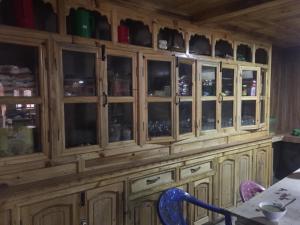 a wooden cabinet with glass doors with a table and chairs at Tribeni Lodge Restaurant And Bar in Phakding