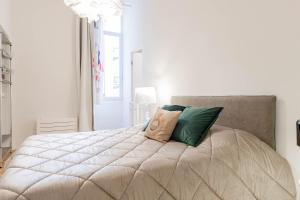 a white bedroom with a large bed with green pillows at H11 [The King's Apartment] Ariston - Centro in Sanremo +28 photos