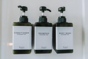 three bottles of shampoo and body wash on a shelf at Manoir Des Curiosités in La Pérade