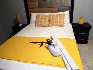 a bed with a yellow blanket and flowers on it at Sem's Guest Cottage in Edenvale