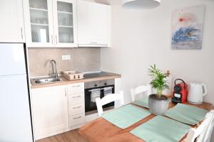 een keuken met witte kasten en een tafel met een potplant bij Old Town Apartment in Corfu-stad +14 foto's