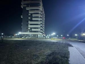 a tall building in a parking lot at night at Apartament 1 in Bistriţa