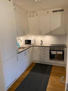a white kitchen with a sink and a microwave at Great 1 bedroom flat on Lidingo in Kottla