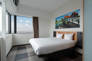 ザーンダムにあるイージーホテル アムステルダム ザーンダムのベッドと大きな窓が備わるホテルルームです。