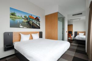 贊丹的住宿－阿姆斯特丹贊丹輕鬆酒店，卧室配有白色的床和墙上的绘画作品
