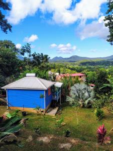 a blue shed in a garden with mountains in the background at Kaz à Rosa in Petit-Bourg