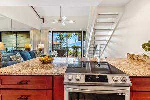 a kitchen with a stove top oven next to a living room at Polynesian Shores 205 in Kahana
