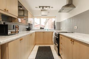 a large kitchen with wooden cabinets and a window at Lovely 3 Bed Home in Ellesmere Port - With Parking - Sleeps 5 in Sutton