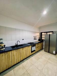 a kitchen with wooden cabinets and a stainless steel refrigerator at Charly Agla-Piscine in Cotonou