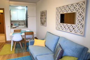 uma sala de estar com um sofá azul e uma cozinha em Monumental Apartment no Funchal