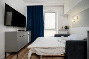 een slaapkamer met een bed en een flatscreen-tv bij Platon Modern Studio in Łódź