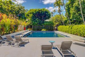 a swimming pool with chairs and a table next to a yard at Pohailani 112 in Kahana