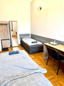 a room with two beds and a desk and a table at Hostel Va Bank in Rzeszów