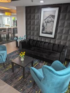 sala de estar con sofá de cuero negro y sillas azules en Quality Inn Danville - University Area, en Danville