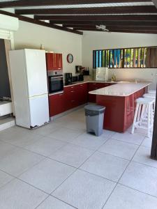 een keuken met rode kasten en een witte koelkast bij LADILAFE in Le Marin
