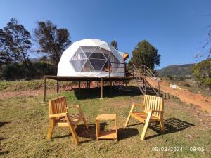 a tent and two chairs and a house on a field at Kodai Glamp in Kodaikānāl