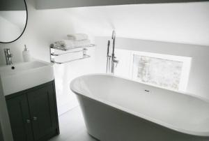 a white bathroom with a tub and a sink at White Cottage deluxe 2 bedroom apartment in Grassington