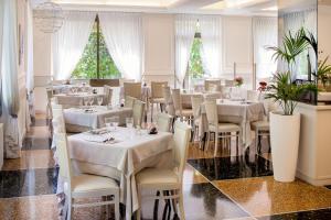 un ristorante con tavoli e sedie bianchi e alberi di Natale di Hotel Mediterraneo a Laigueglia