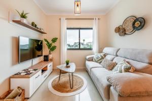a living room with a couch and a tv at Serenity Costa da Caparica in Almada