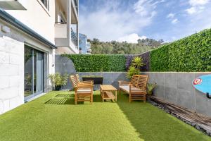 a patio with chairs and a table on the grass at Serenity Costa da Caparica in Almada