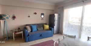 Deluxe cozy chalet in Malibu Sokhna في العين السخنة: غرفة معيشة بها أريكة زرقاء وثلاجة