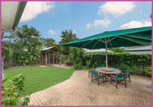 un patio con mesa, sillas y sombrilla en The Ultimate Queensland Holiday!, en Aitkenvale