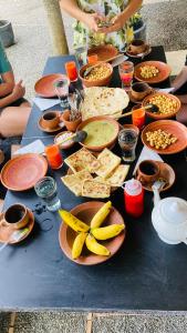 a table with plates of food on it with bananas at Ayubowan Hiriketiya in Dickwella