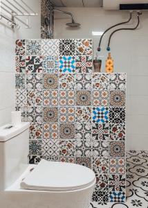 a bathroom with a toilet and a tiled wall at New Dap Hostel (in Grape Town) in Turfan