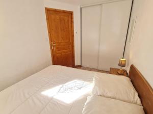 1 dormitorio con cama blanca y puerta de madera en Les Chalets d Or - B03 - Appt terrasse 4 pers, en Les Deux Alpes