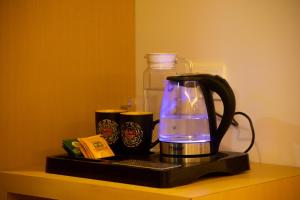 a coffee maker sitting on a shelf with two cups at The Grand ARK in Gangtok