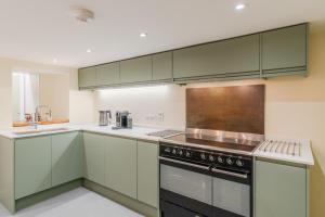 a kitchen with green cabinets and a stove at The Weir House in Symonds Yat