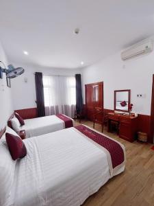 a hotel room with three beds and a desk at Quốc Khánh Hotel Da Nang in Da Nang