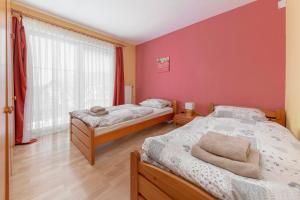 2 Betten in einem Zimmer mit roten Wänden in der Unterkunft Apartments Žnidar in Spodnje Gorje