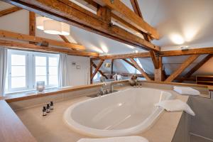 una grande vasca bianca in una stanza con soffitti in legno di Hotel Weissenstein a Oberdorf