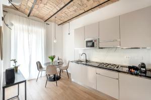 uma cozinha com armários brancos e uma mesa com cadeiras em W STUDIO TERMINI em Roma