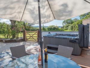 a table with an umbrella on a deck with a hot tub at Cilbronnau Lodge Cardigan in Llechryd