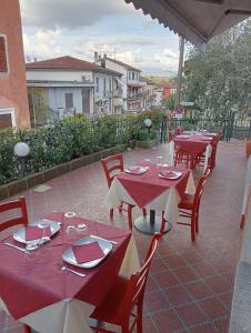 une rangée de tables et de chaises rouges sur une terrasse dans l'établissement San Quirico Locanda ristorante pizzeria, à Barbarasco
